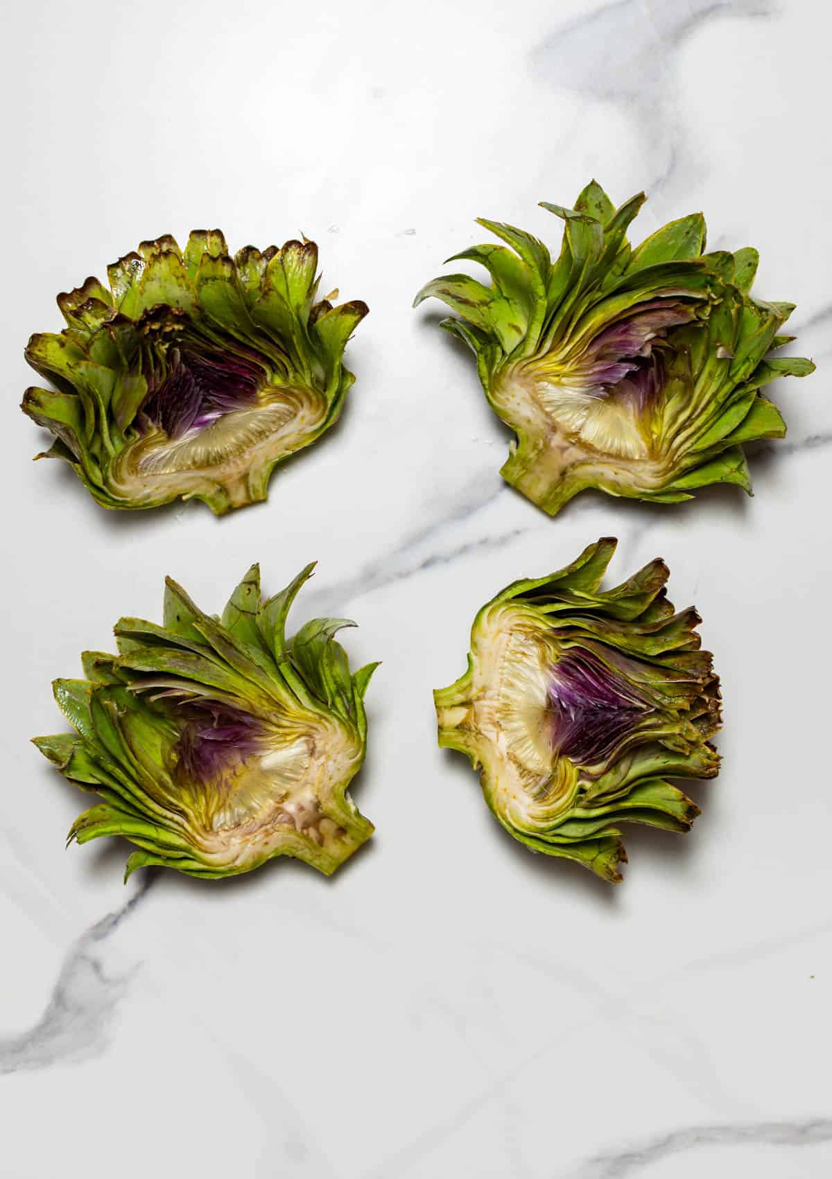 four artichoke hearts on a white surface