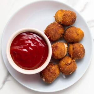 chili cheese nuggets on a plate with ketchup on the side