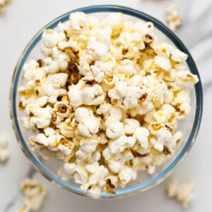 overlay shot of maple popcorn in a glass bowl on a white surface