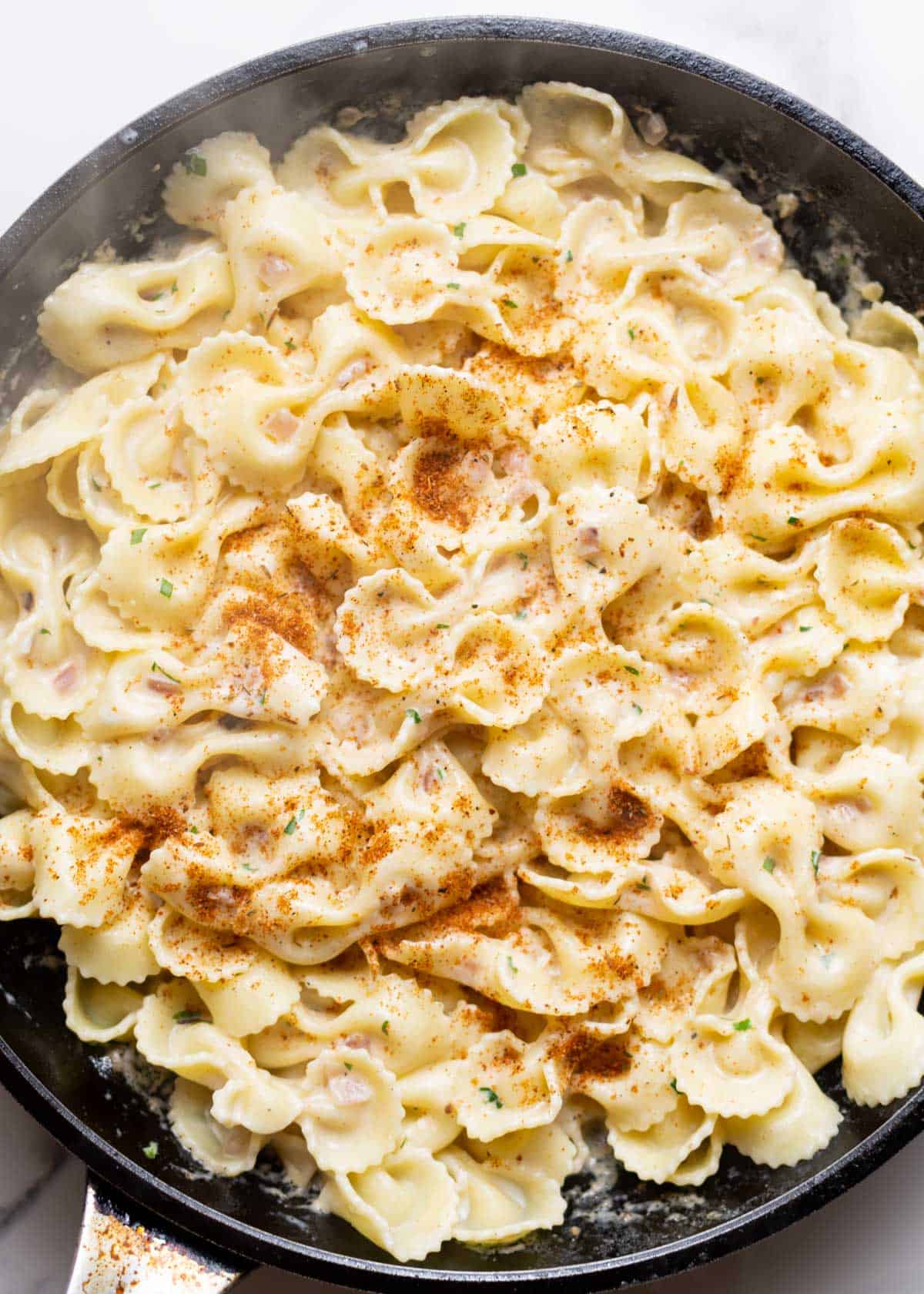 Cajun farfalle Alfredo in a skillet.