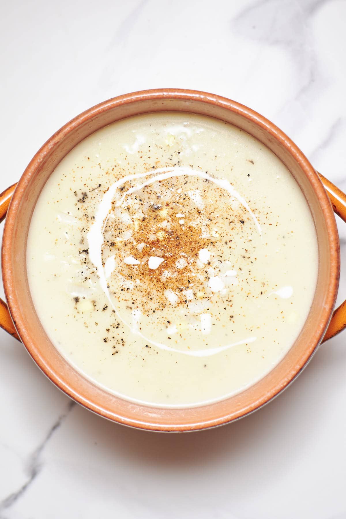 overlay shot of potato soup with splash of heavy cream on top.