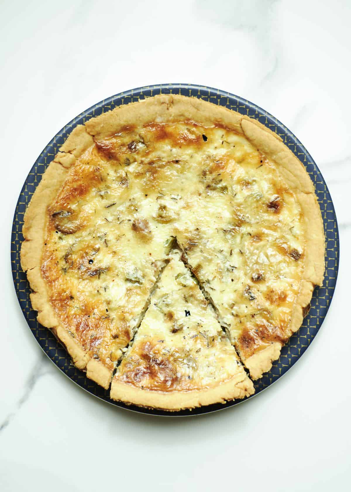 leek and mushroom quiche sliced on a blue plate 