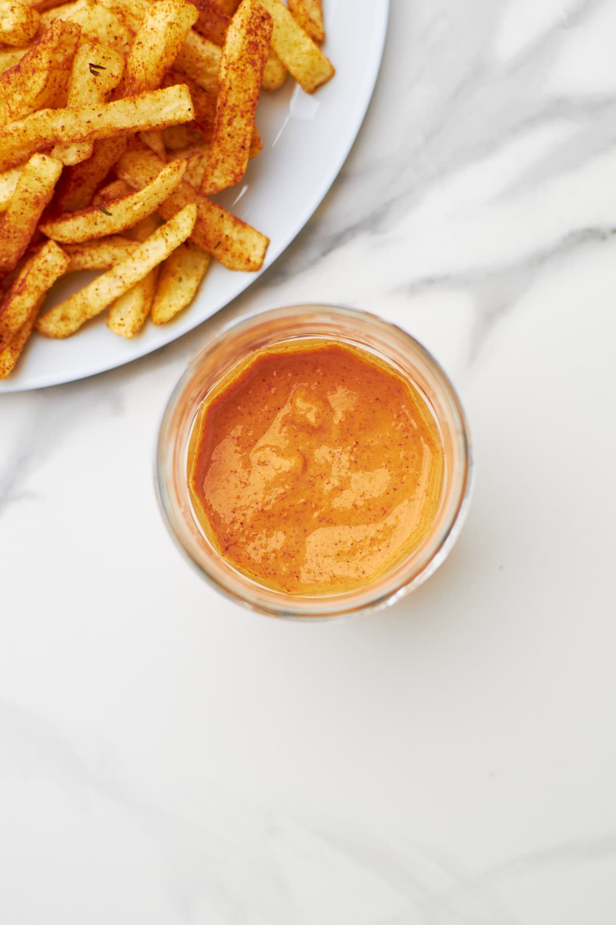 closeup of boom boom sauce with bowl of fries on the side.