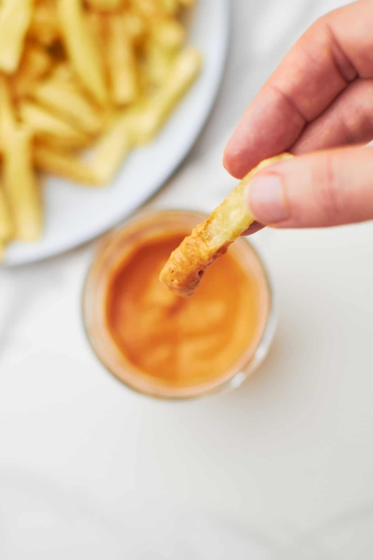 fries dipped in boom boom sauce jar.