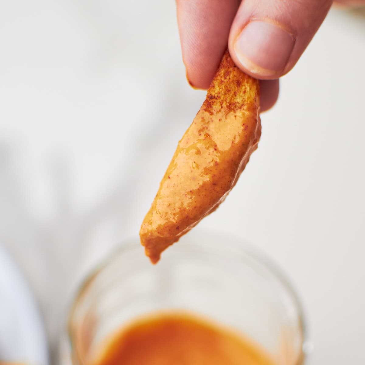 close up shot of a Cajun seasoned fries dipped in boom boom sauce. 