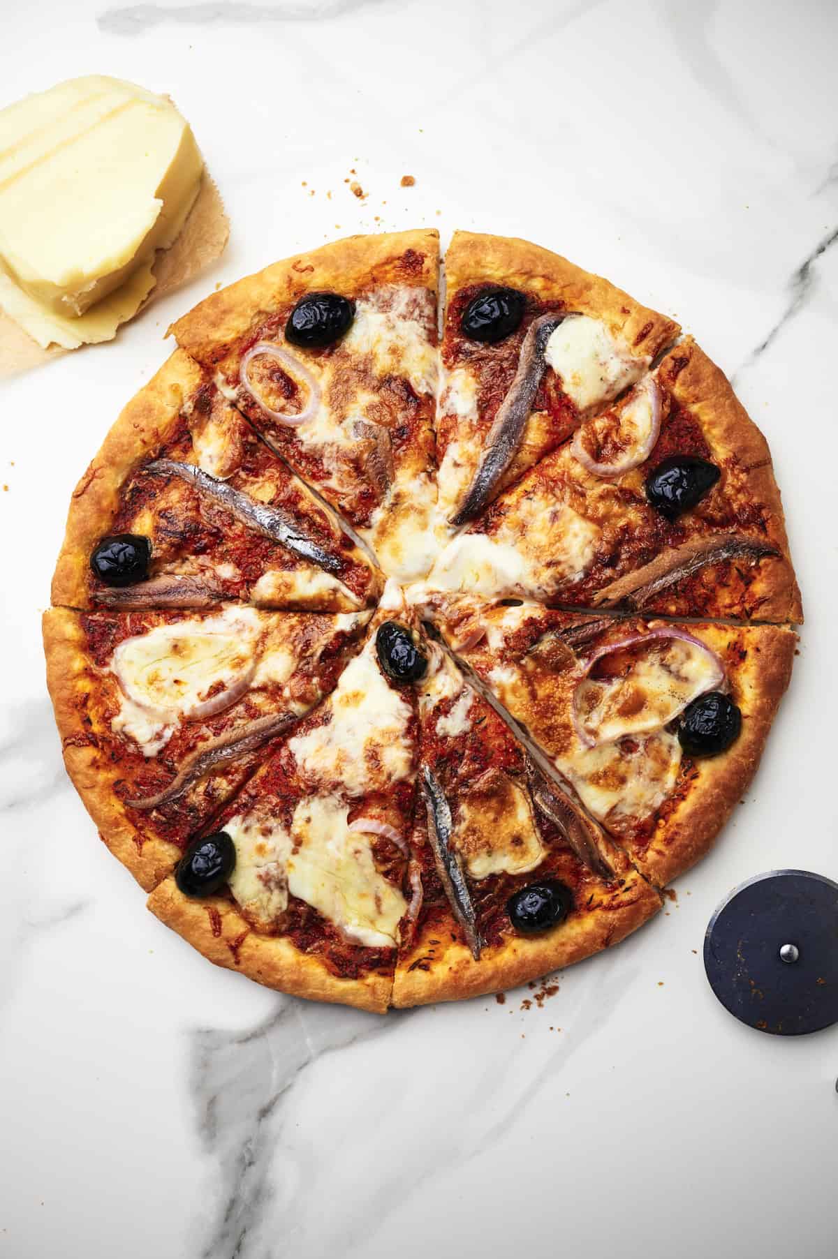 sliced anchovy pizza on countertop.