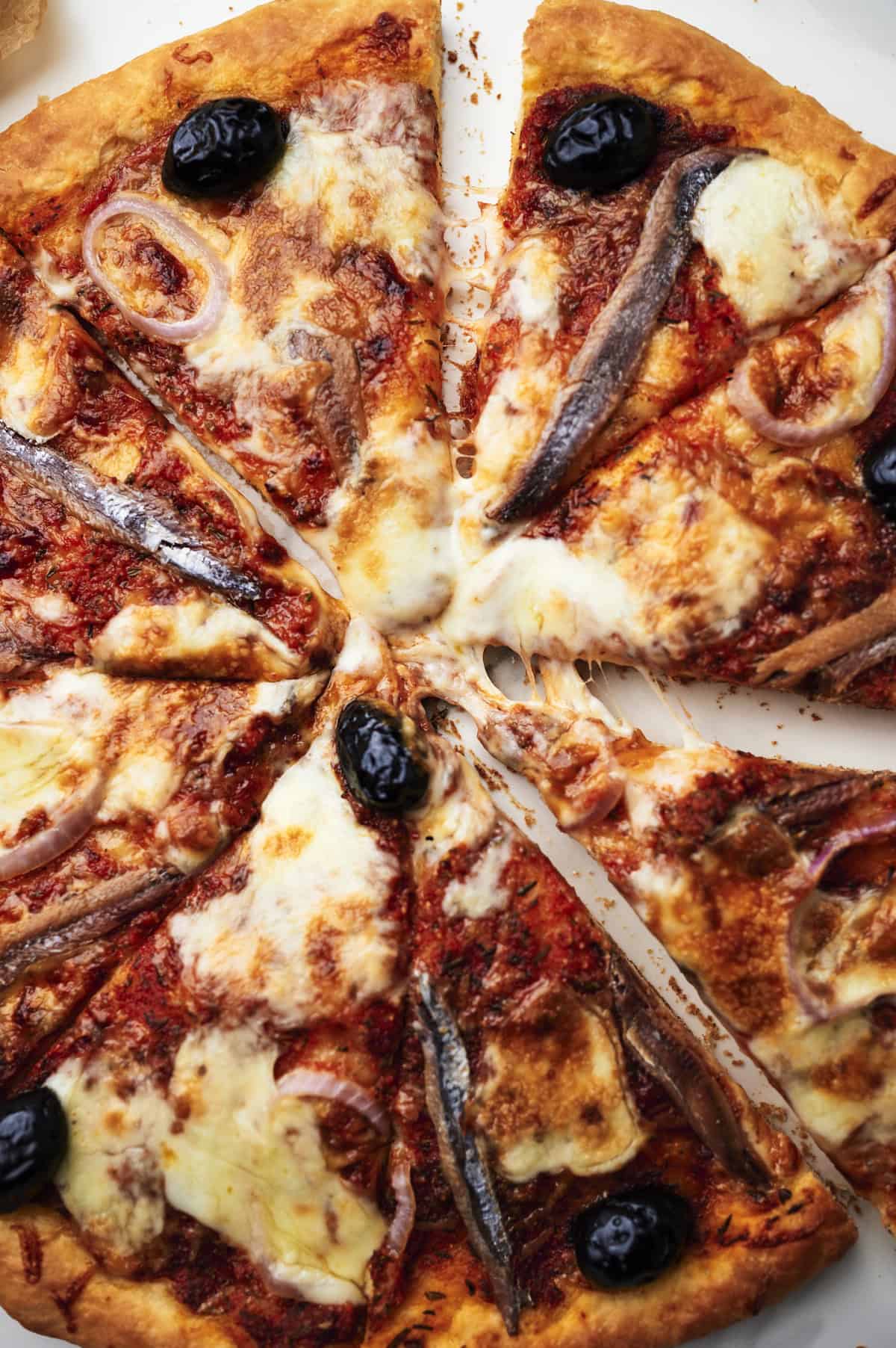 baked anchovy pizza on cutting board.