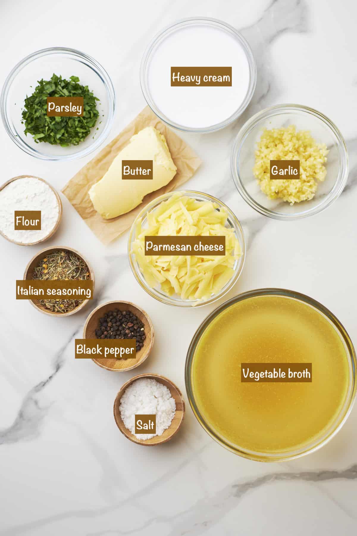 White marble counter top with bowls of ingredients to make Parmesan garlic sauce.