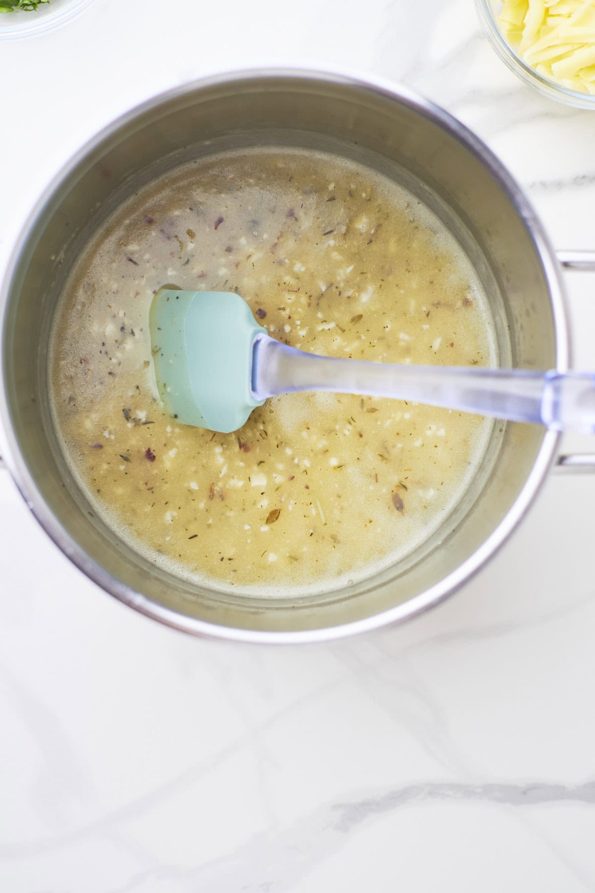 Large white sauté pan filled with ingredients to make Parmesan cream sauce.