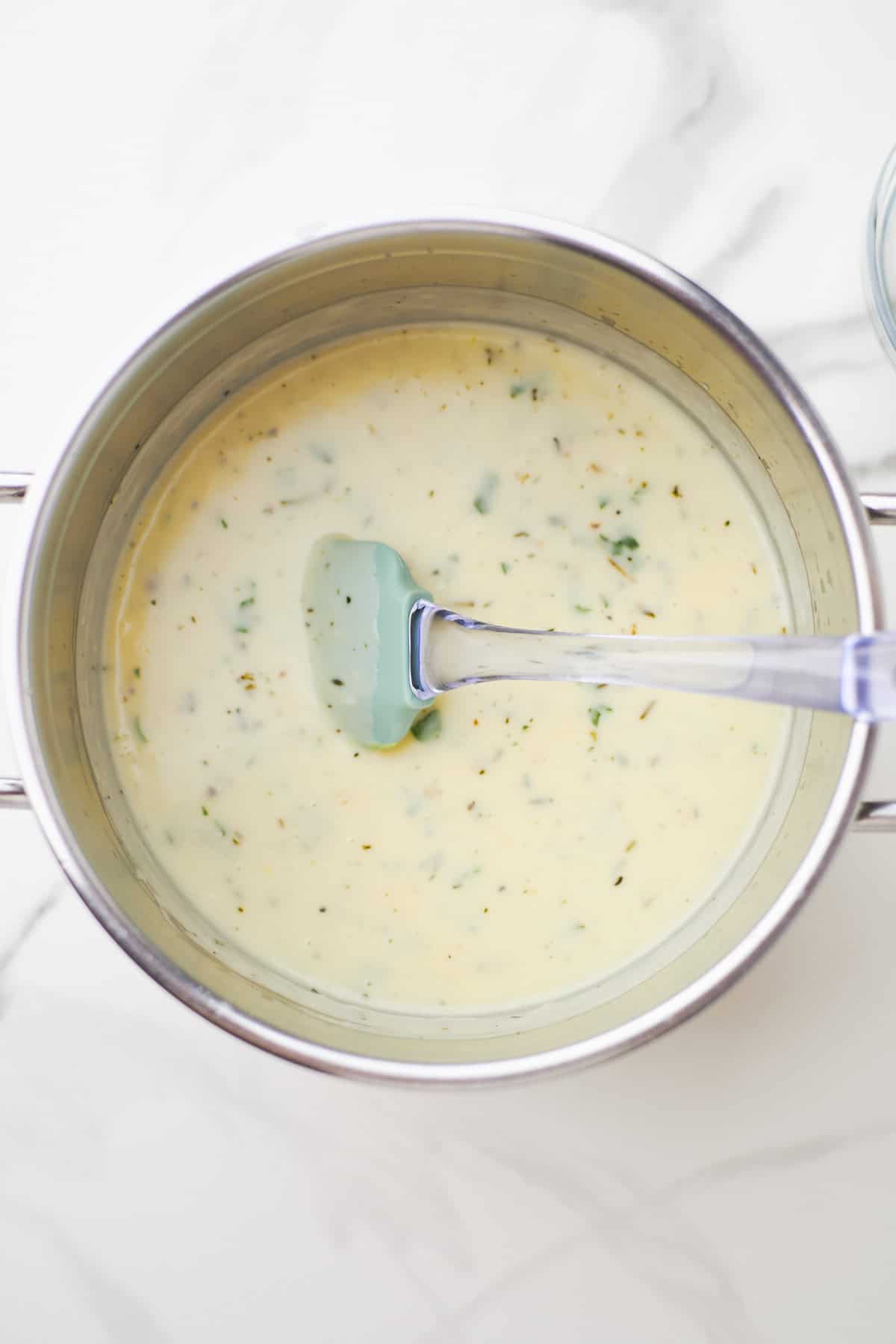 Large white sauté pan filled with creamy Parmesan garlic sauce.