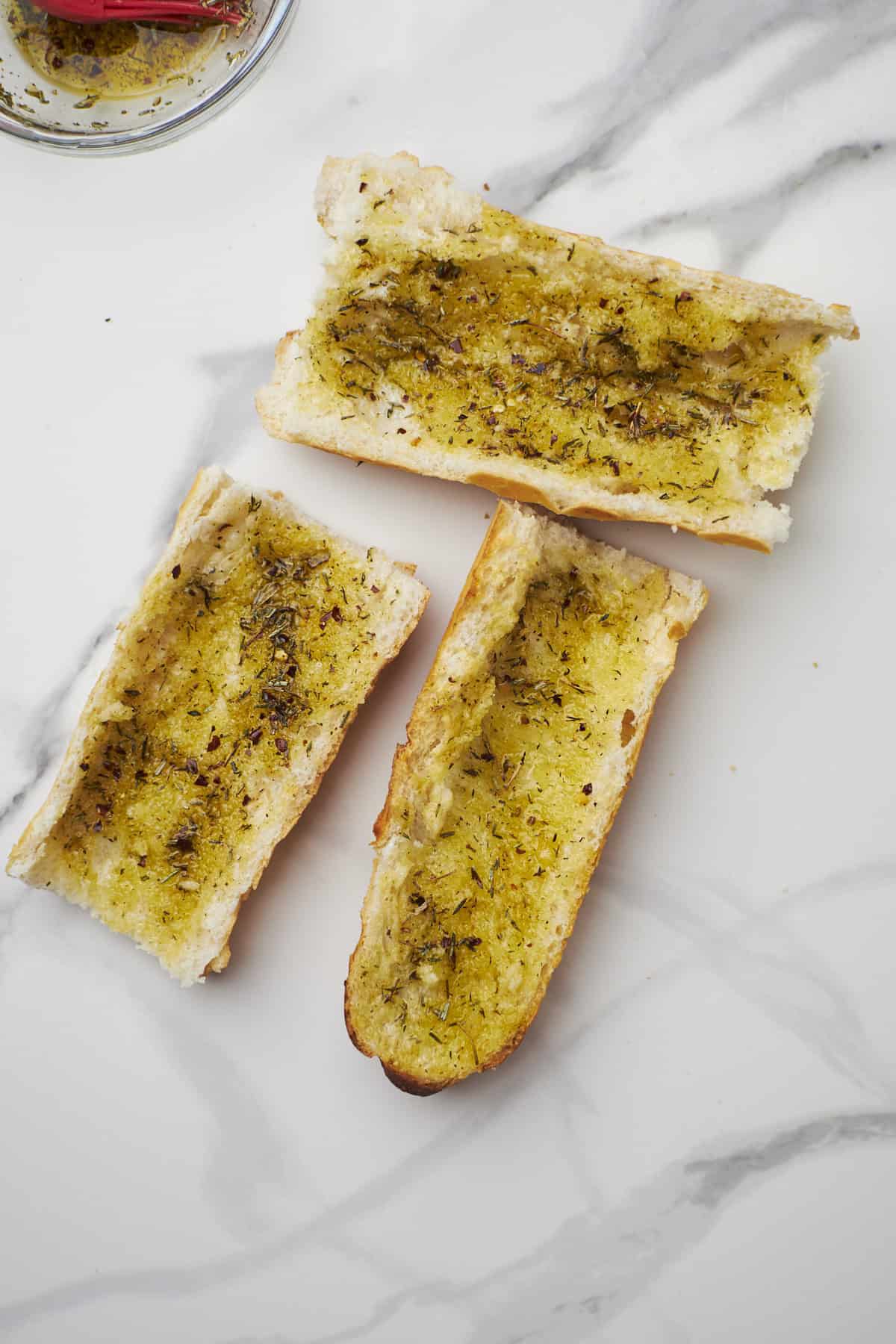 french loaf halves brushed with olive oil and italian seasoning.