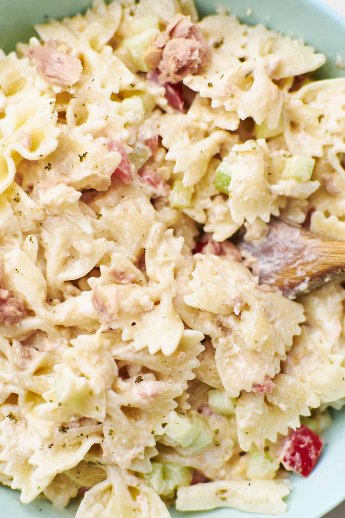 closeup view of a bowl full of ranch pasta salad and a wooden spoon on the right. 