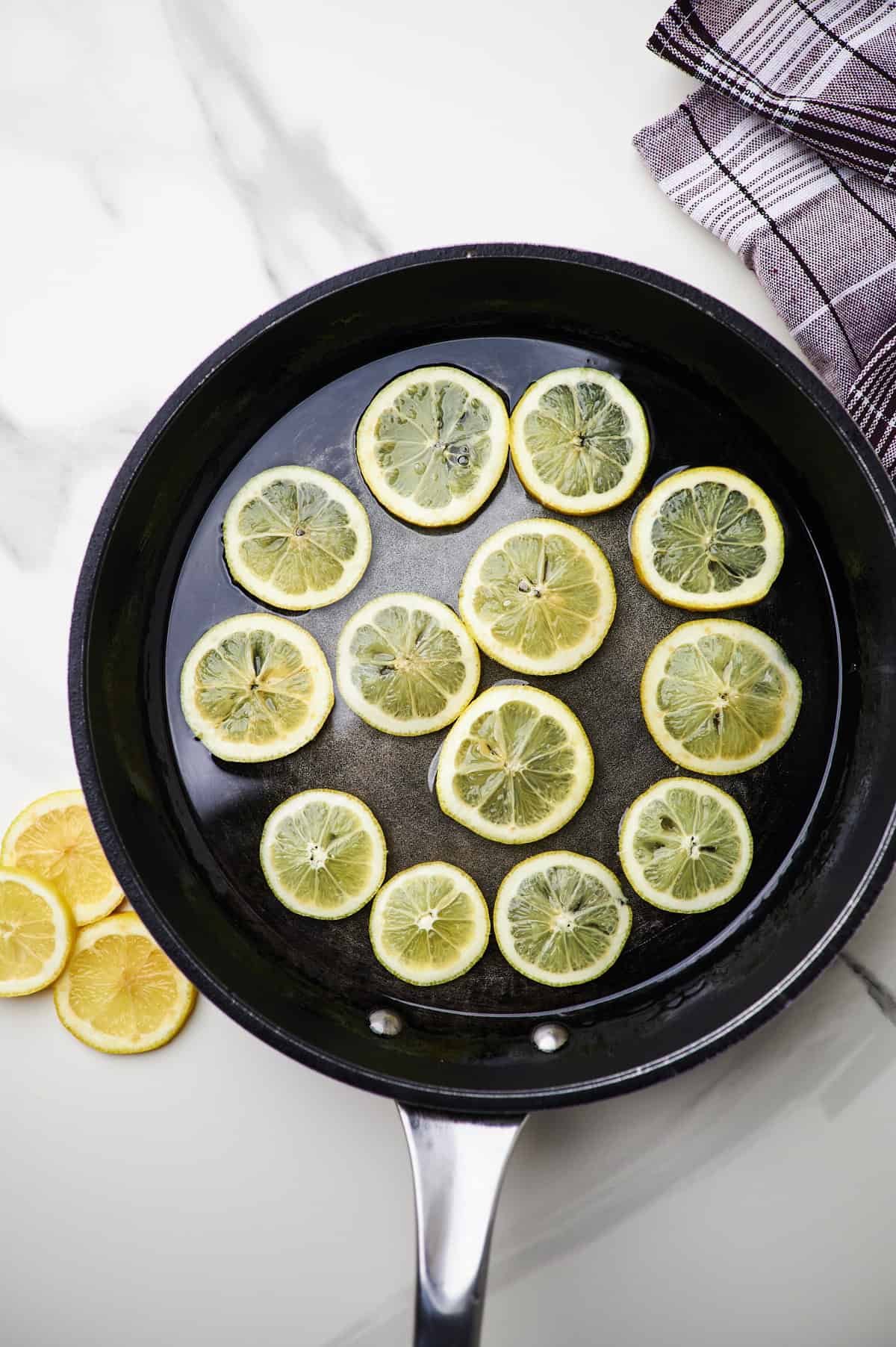 lemon slices being cooked in simple syrup.