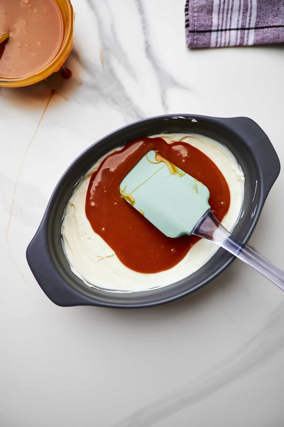 caramel dip being spread on top of cream cheese layer