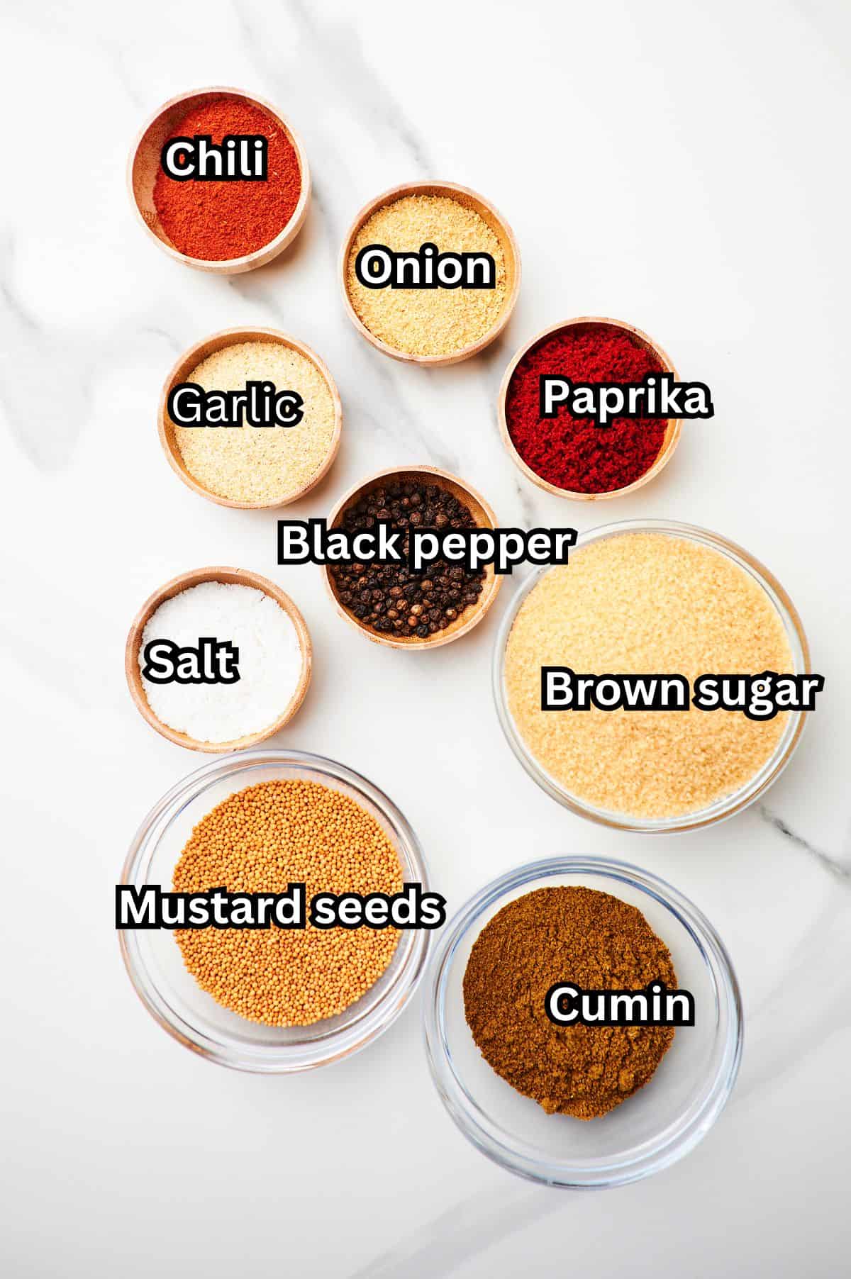 White marble counter top with bowls of ingredients to make homemade rib rub.