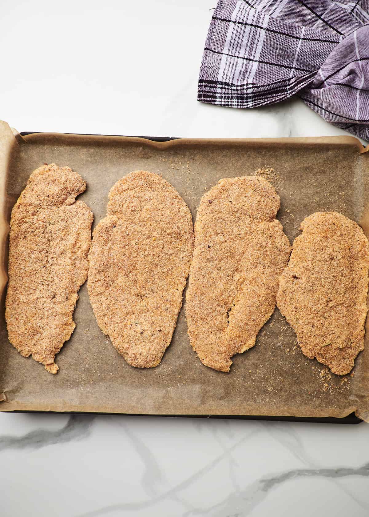 Panko crusted chicken breasts on a sheet pan. 