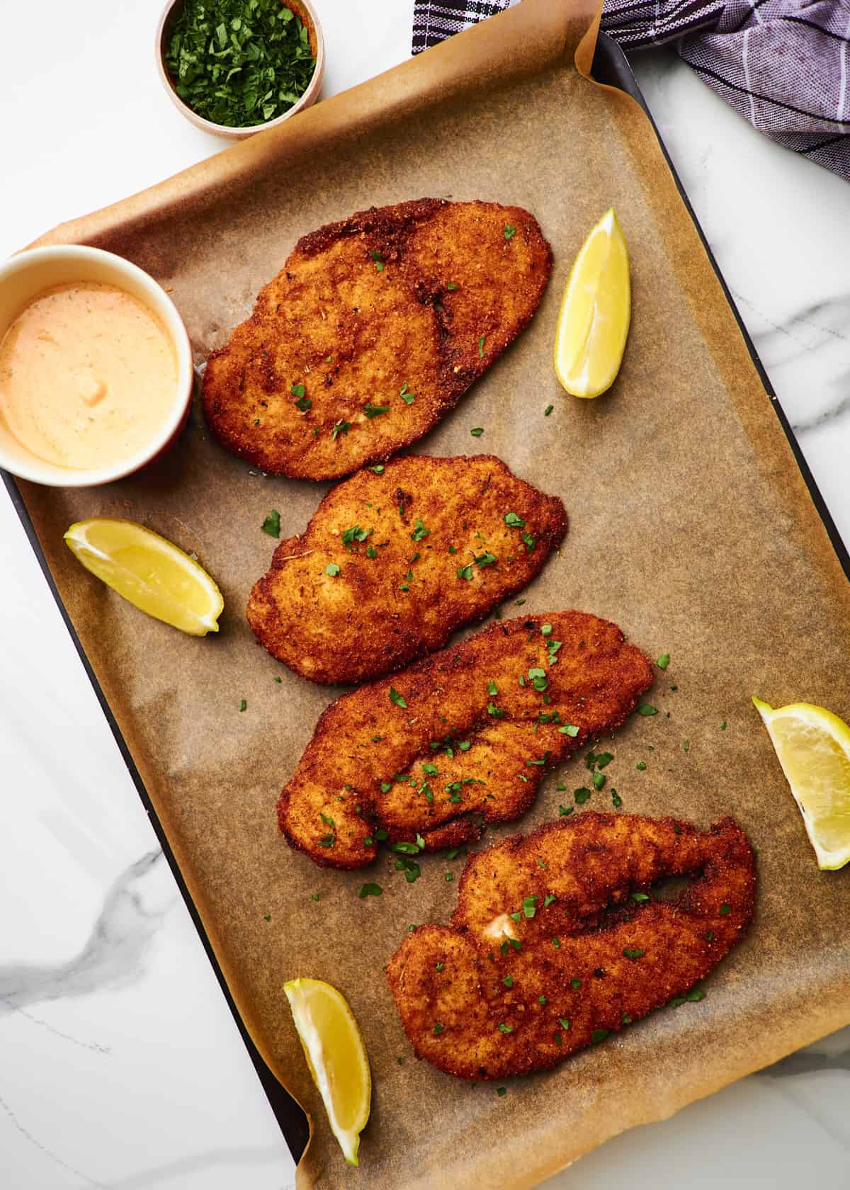 Metal sheet pan with Panko crusted chicken garnished with fresh parsley. 