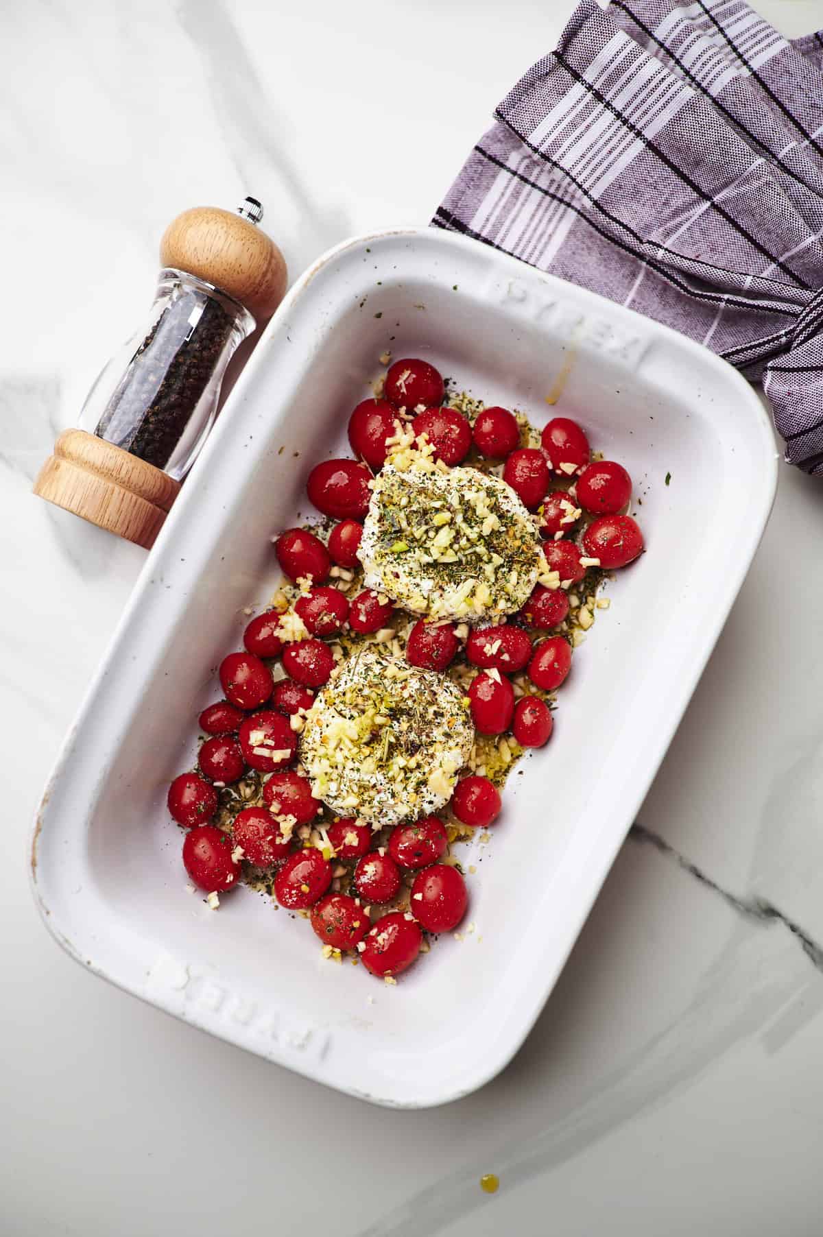 process shot showing the boursin cheese rounds and tomatoes in a baking dish before baking.