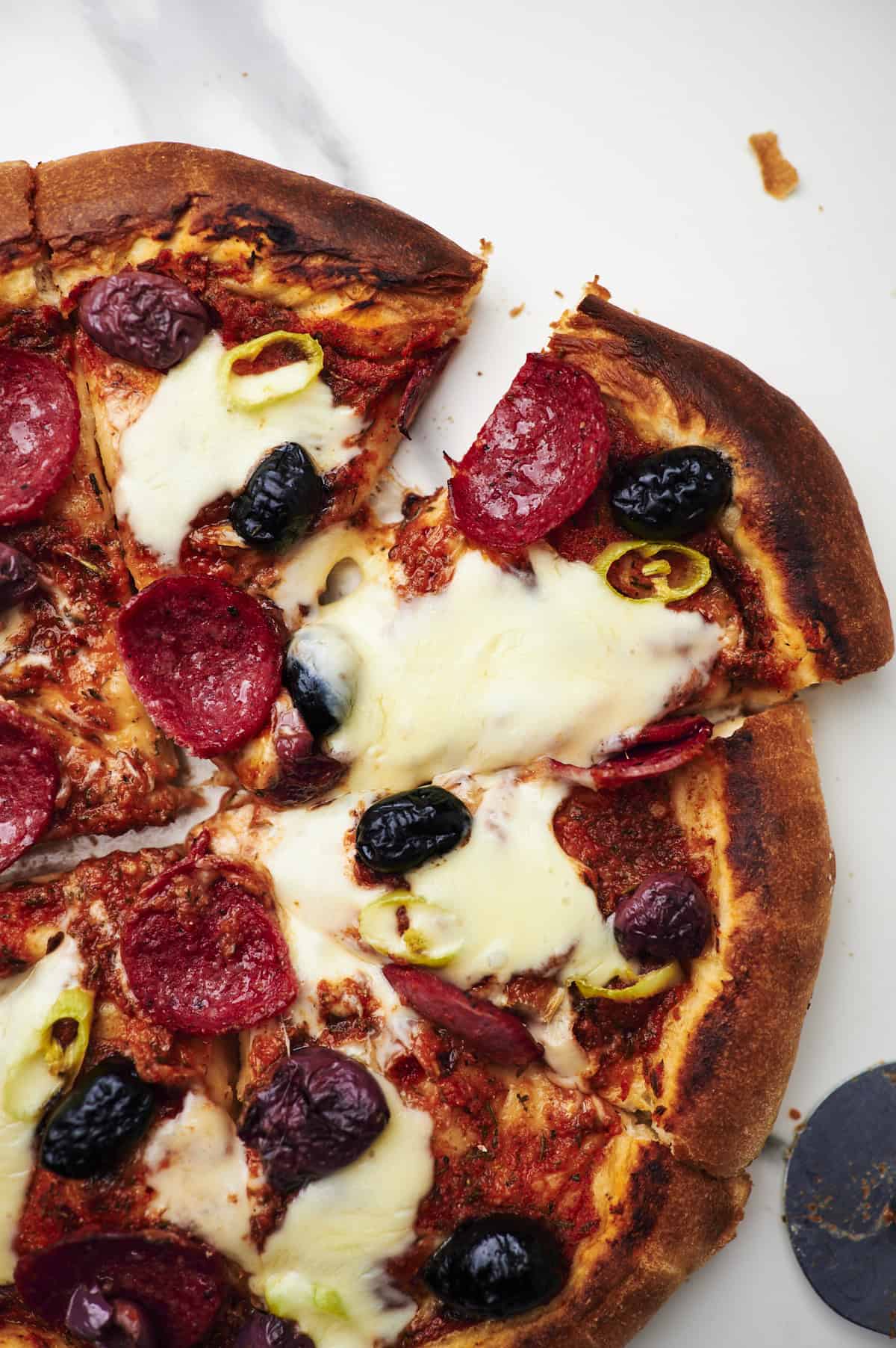 spicy diavola pizza with hot salami on counter marble, one slice cut out.