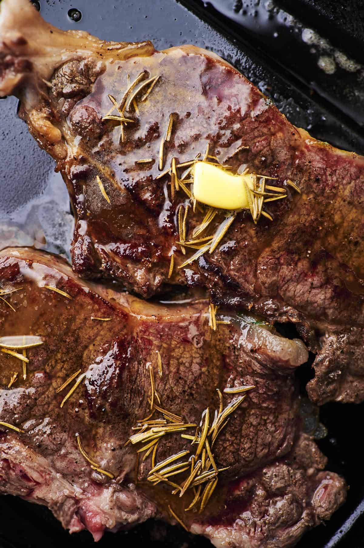 steak with garlic butter and thyme on griddle.