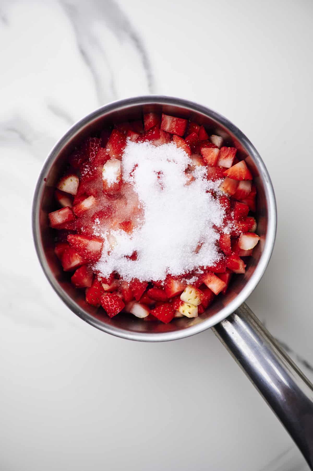 diced strawberries with sugar and lemon juice in saucepan.