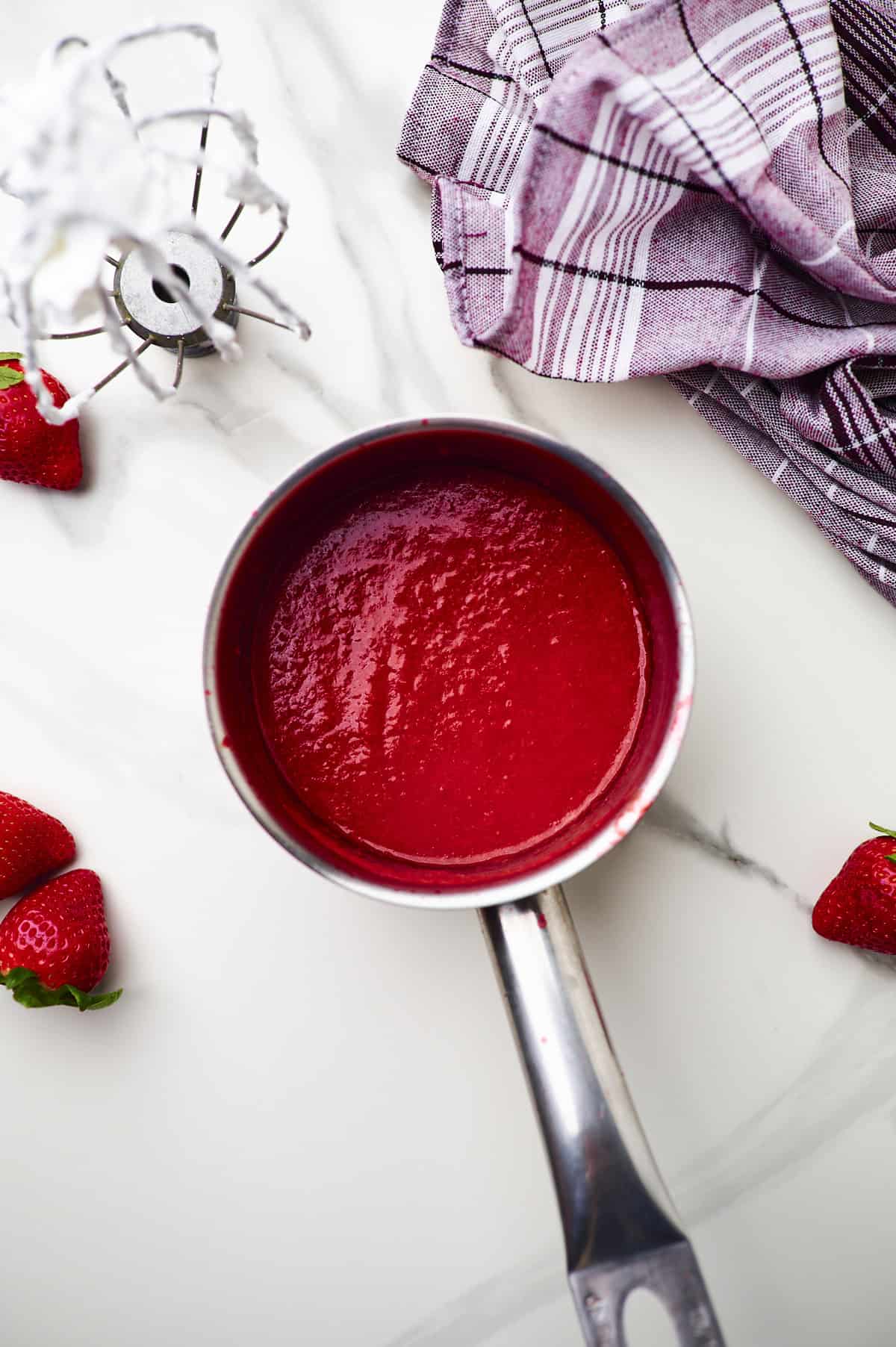 Reduced strawberry puree in saucepan.