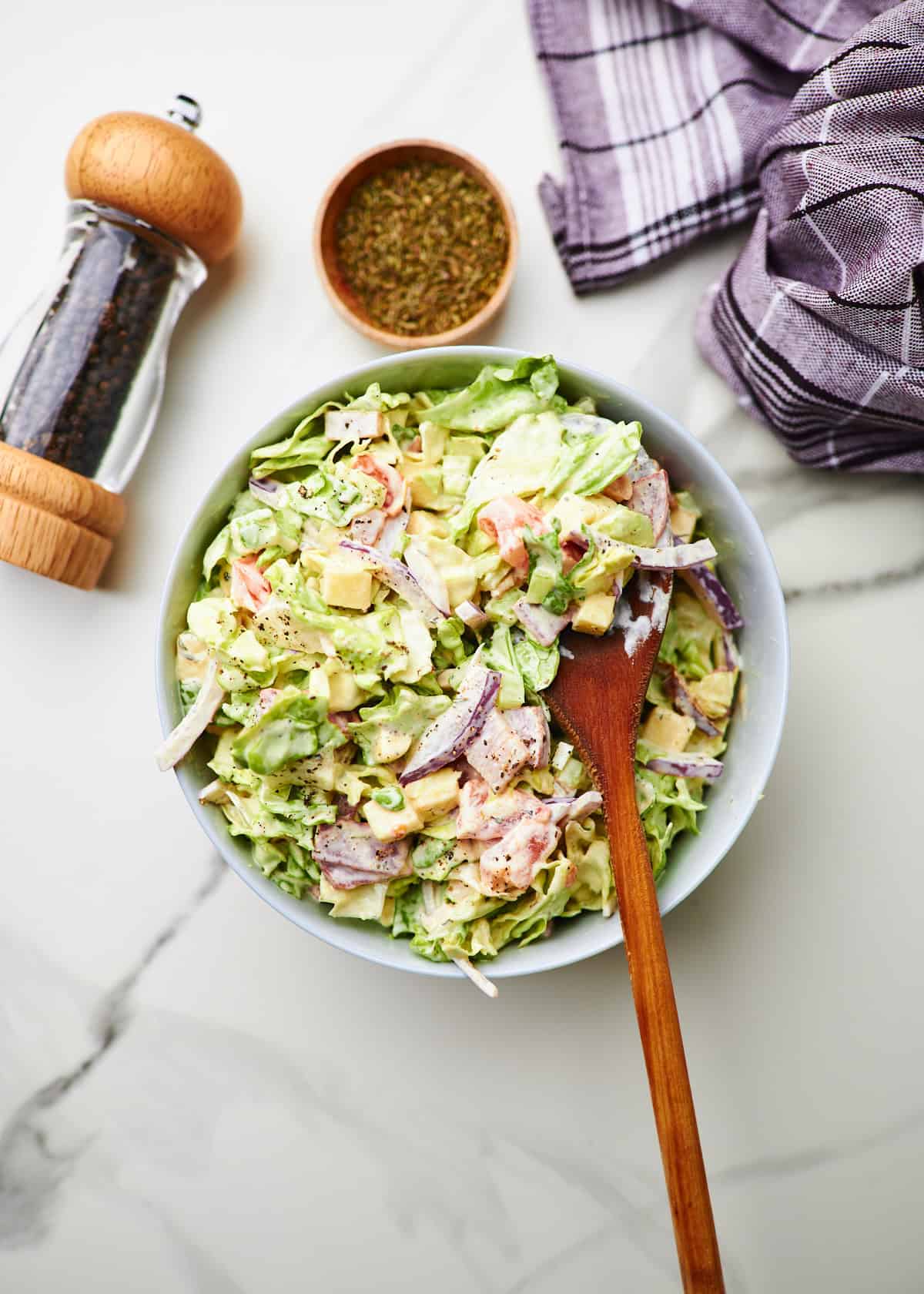 Italian grinder salad in a bowl with a wooden spoon