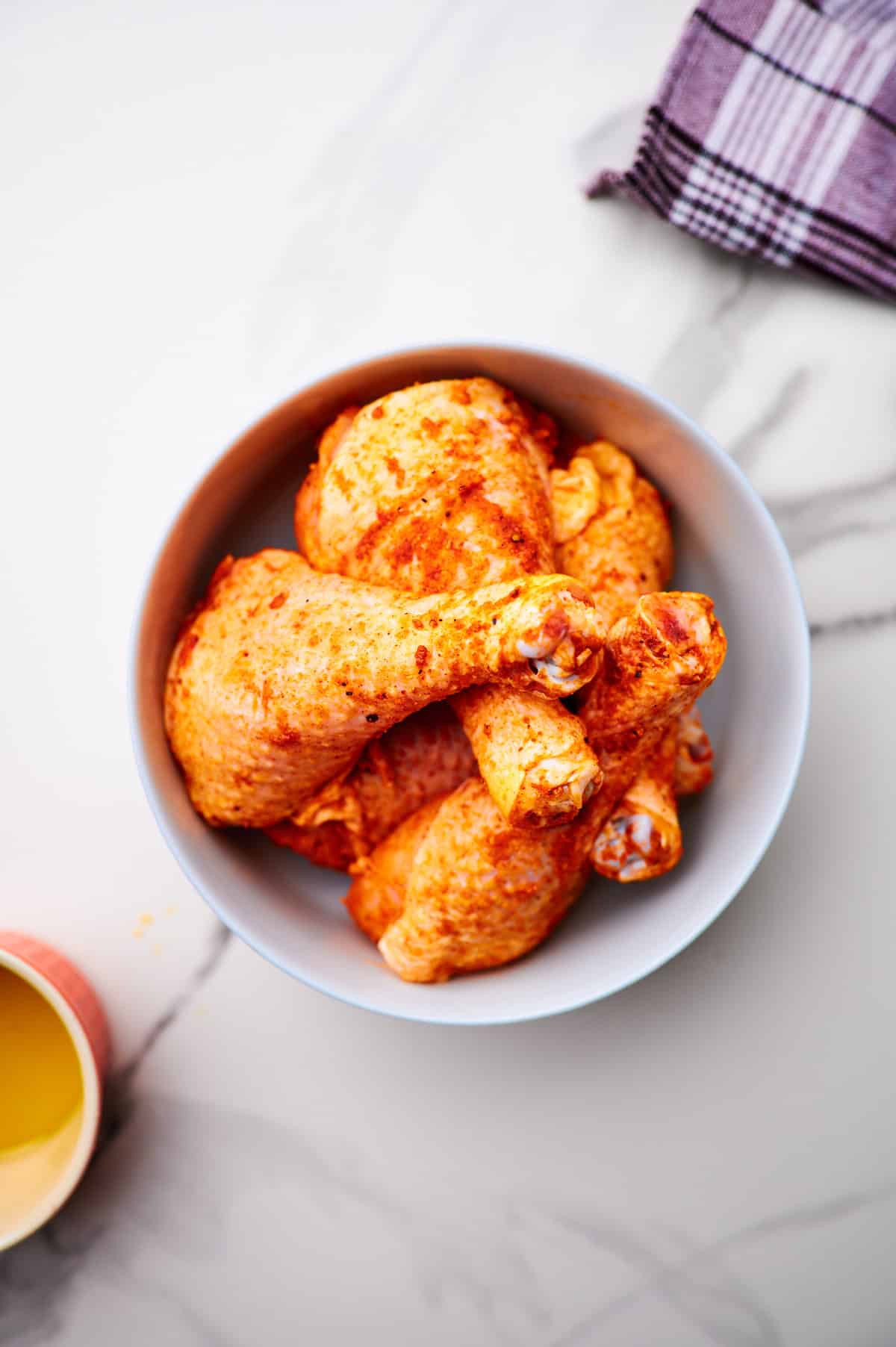 Close up photo showing drumstick in a bowl, shaken with seasonings.