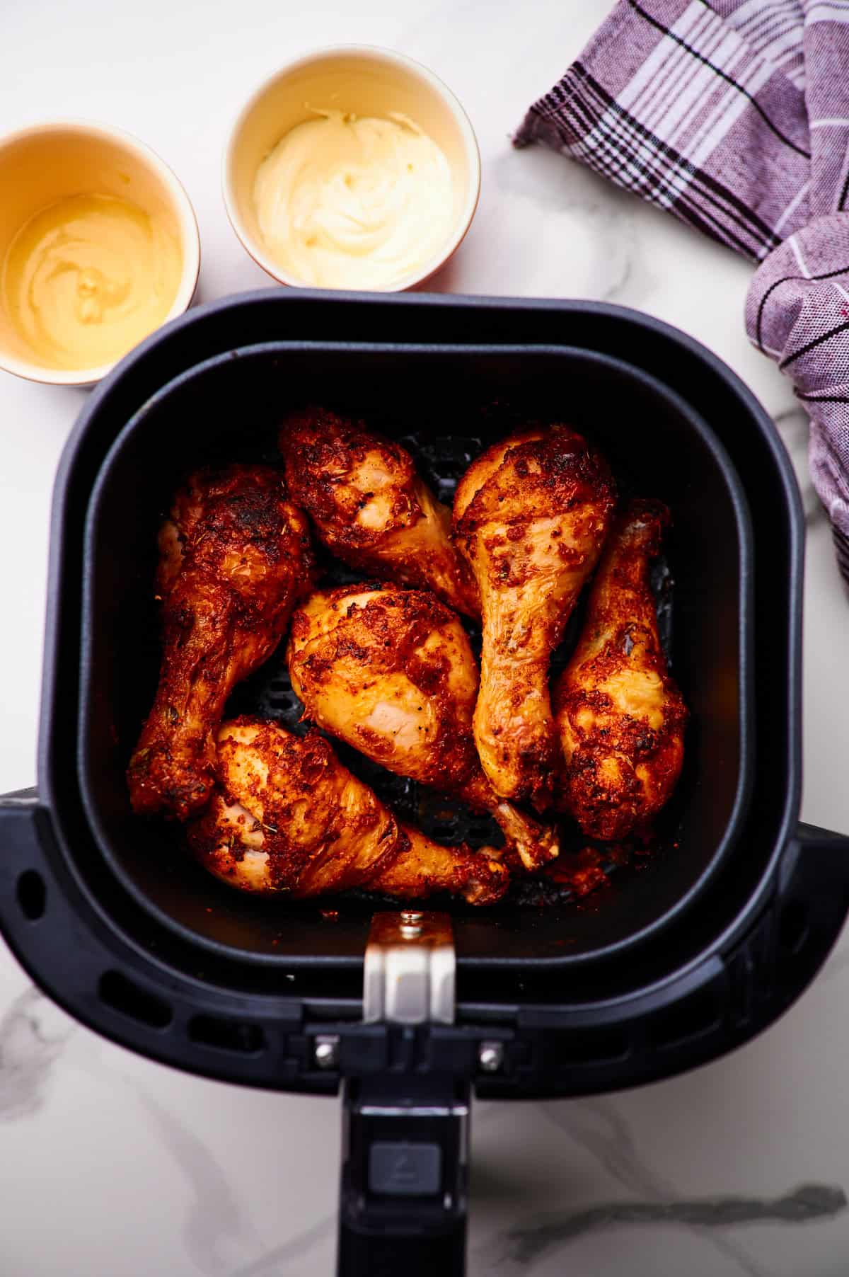 Crispy chicken drumsticks in the air fryer basket.