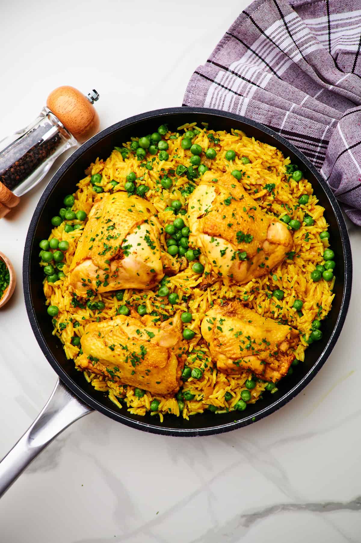 chicken and yellow rice with peas on white board with garlic, parsley.