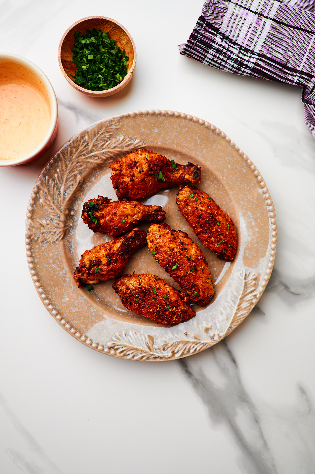 Closed up of seasoned crispy air fryer chicken wings on a plate ready to serve.