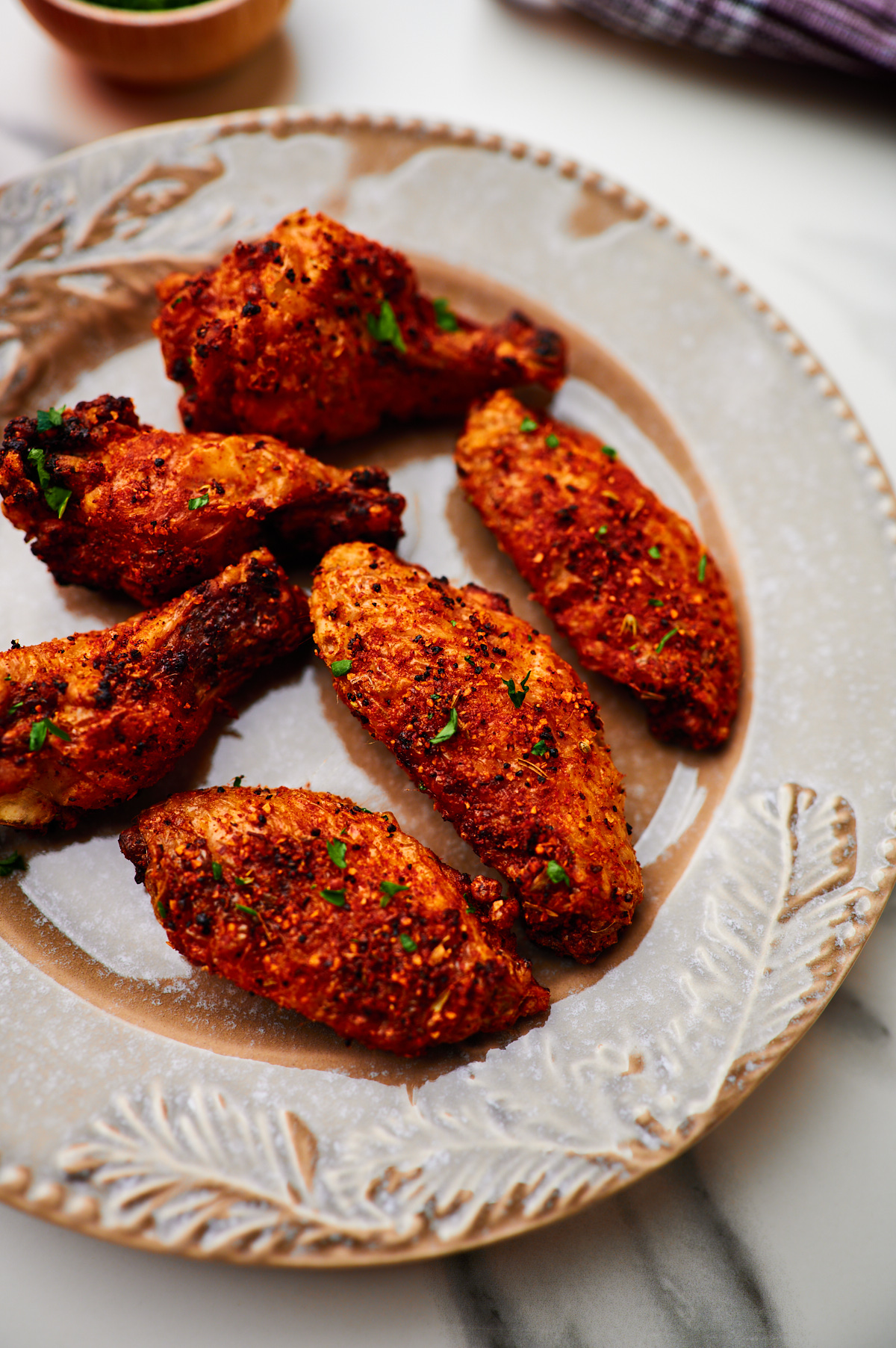 Closed up of seasoned crispy air fryer chicken wings on a plate ready to serve.