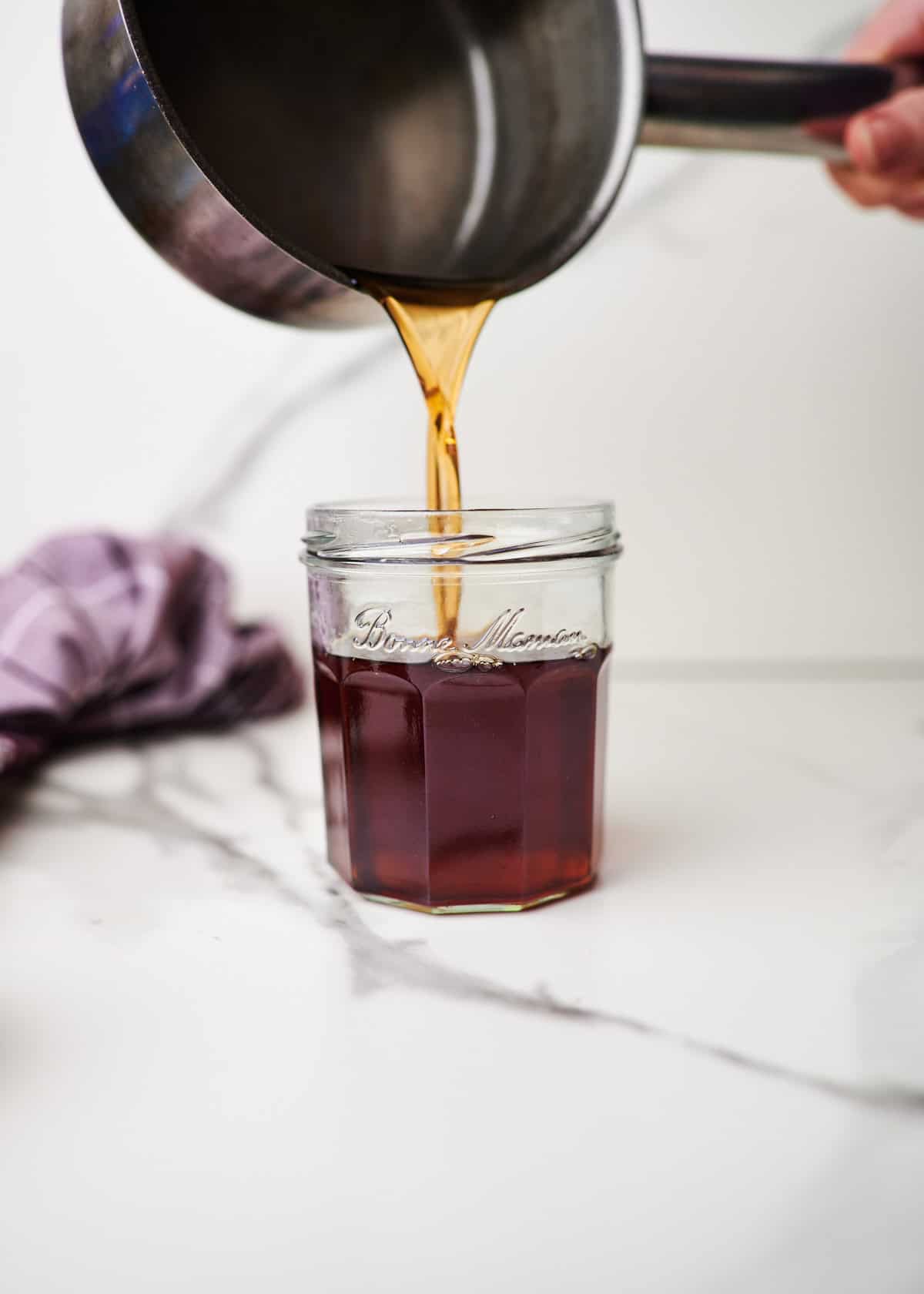 Brown sugar syrup being poured into a mason jar.