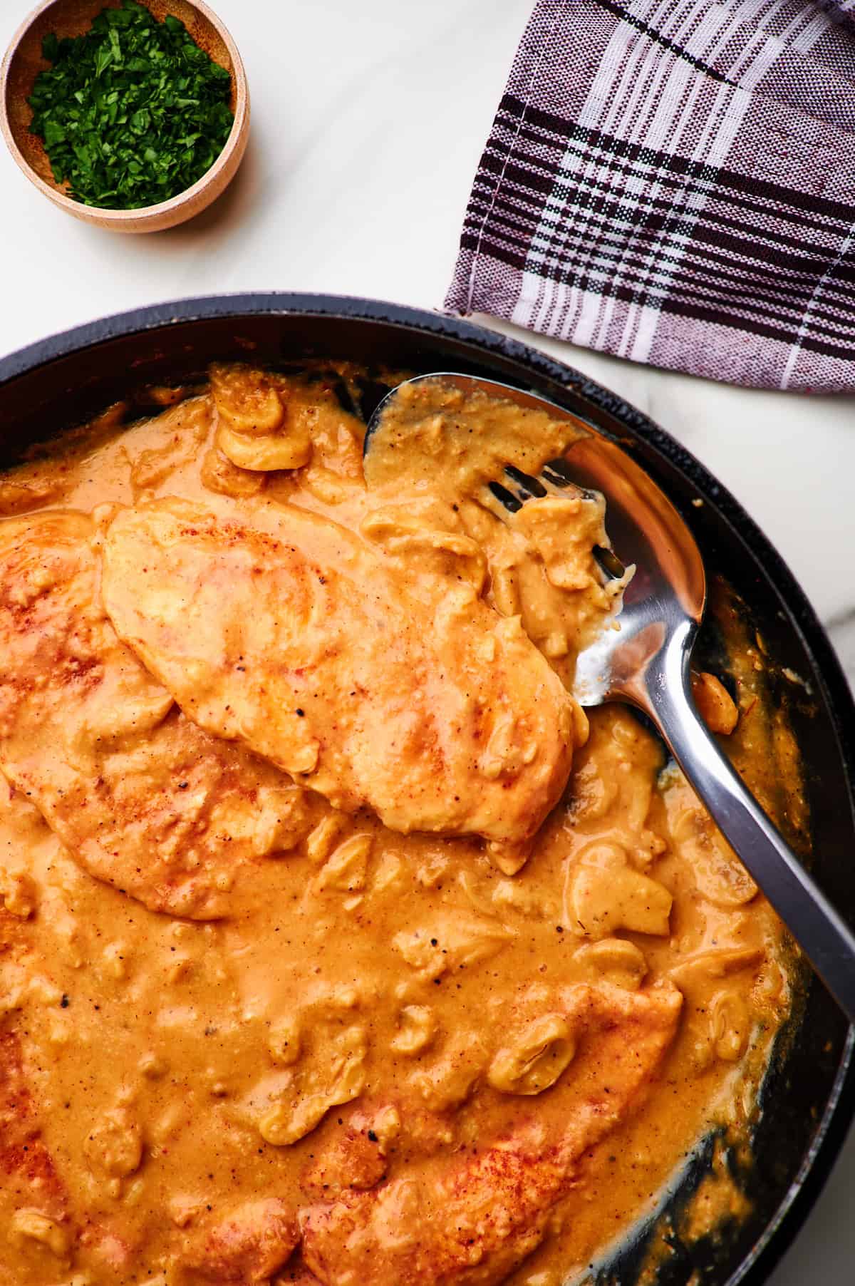 Creamy mushroom sauce chicken in a skillet with a spatula for serving.