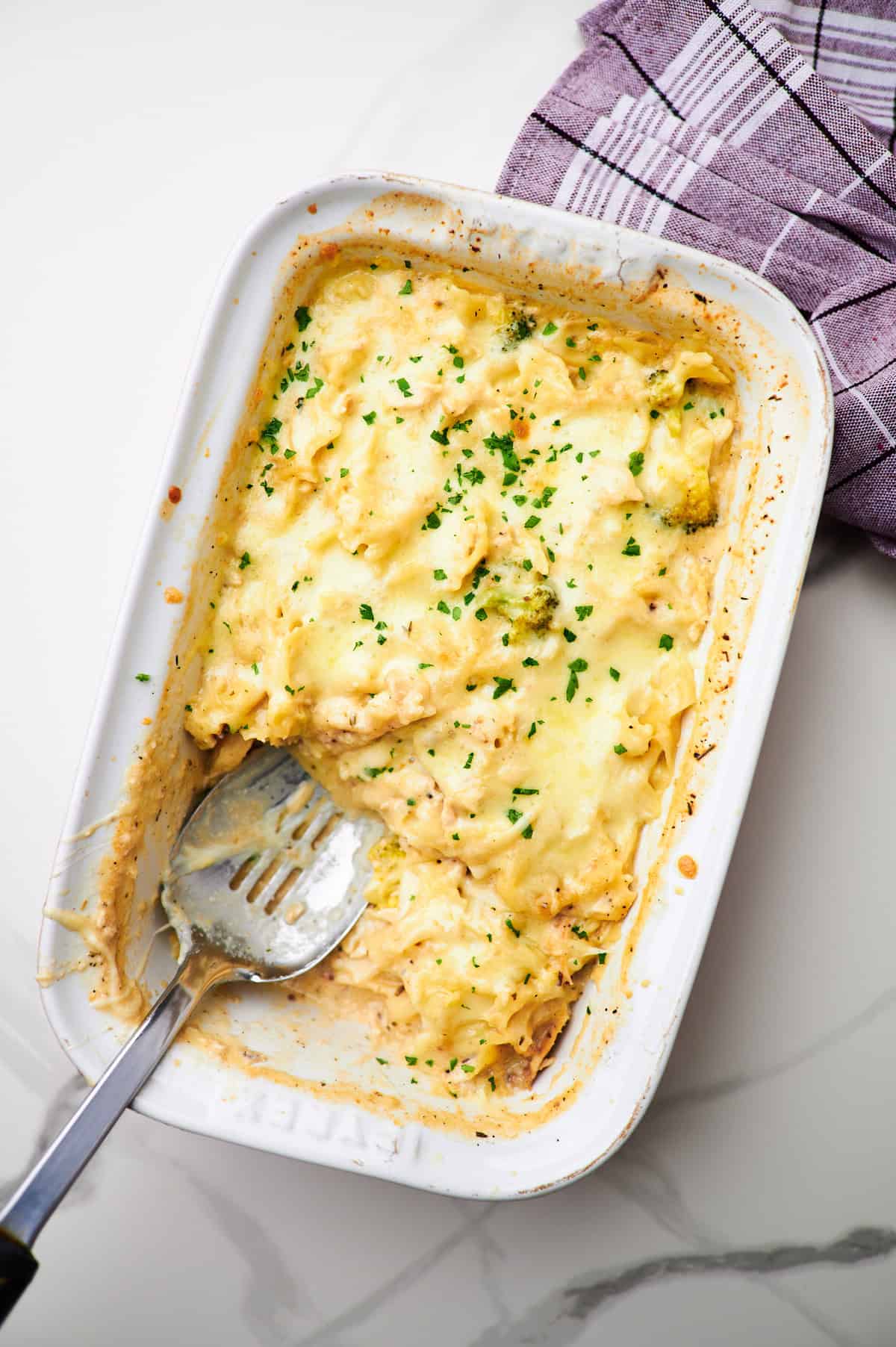 A pasta dish with a serving spoon in it. 