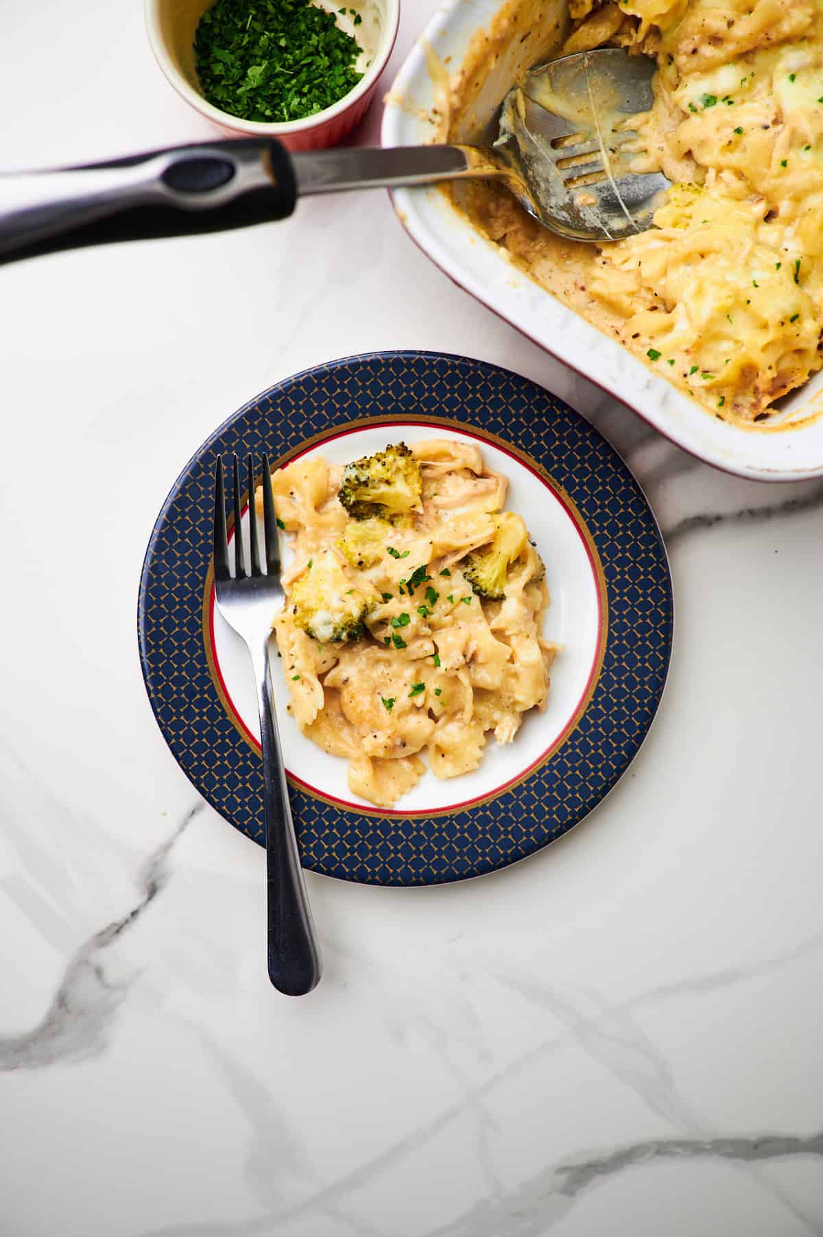 A serving plate with the casserole dish behind it. 