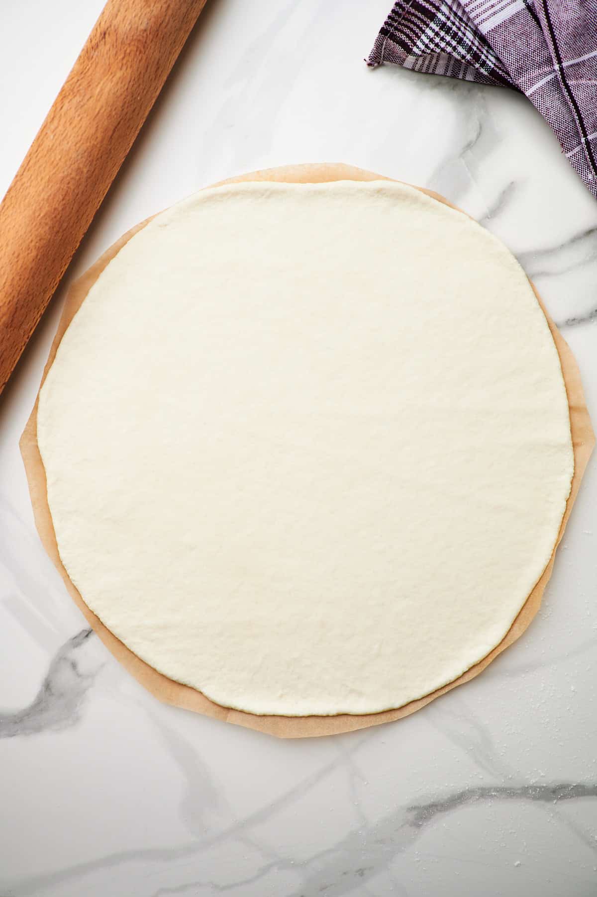 Rolled out high protein pizza dough on a piece of parchment paper.