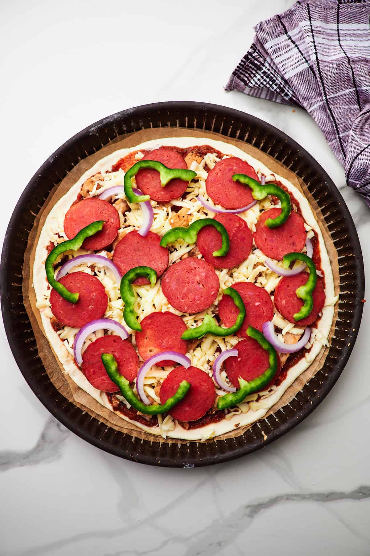 Raw high protein pizza on a piece of parchment paper ready to go into the oven.