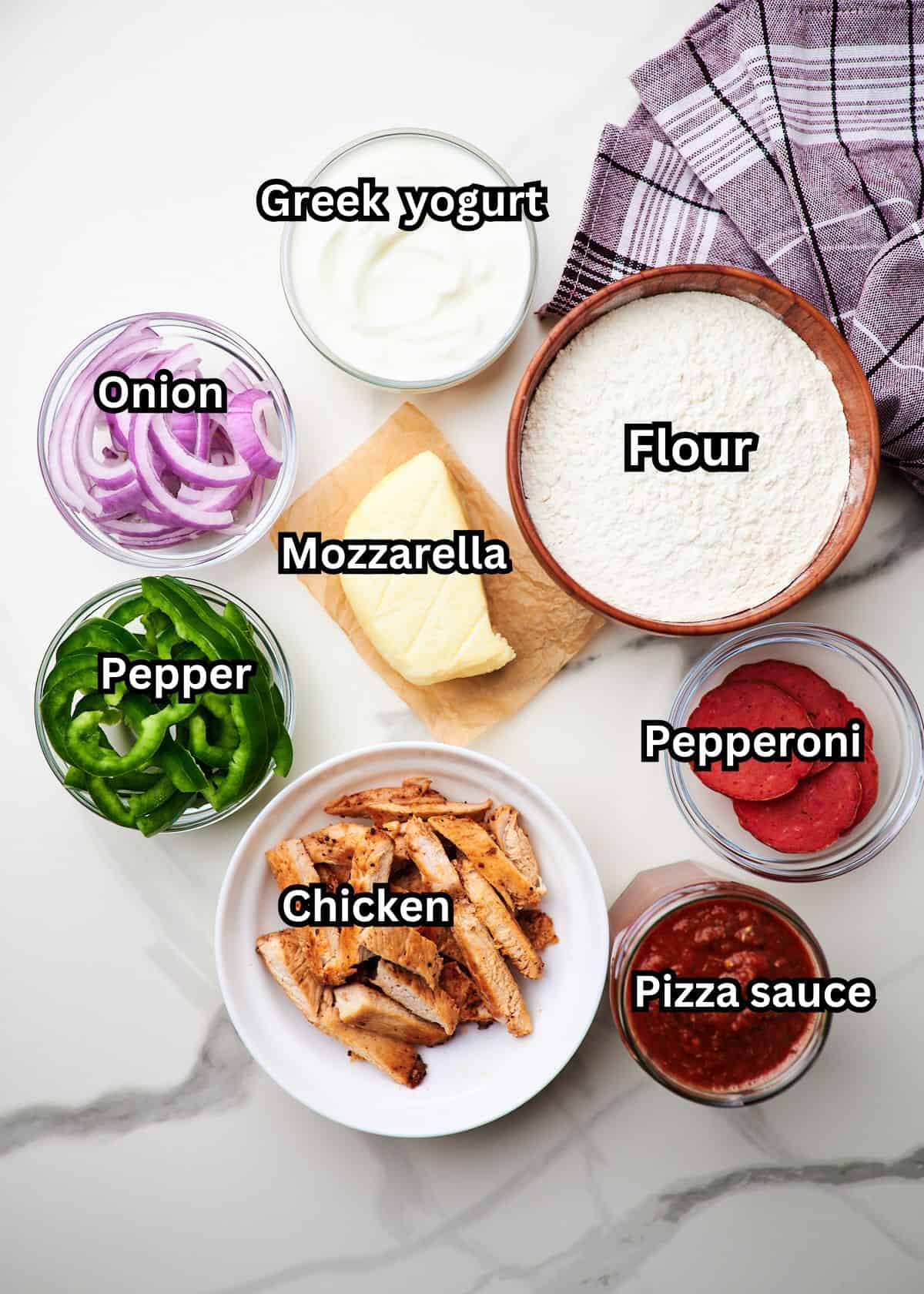 Ingredients for high protein pizza on a countertop with labels.