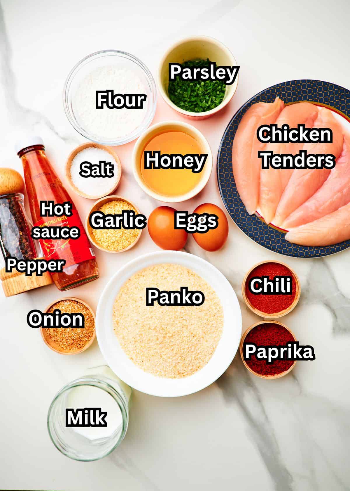 ingredients needed to make hot honey chicken tenders measured out into bowls and plates on a white tabletop.