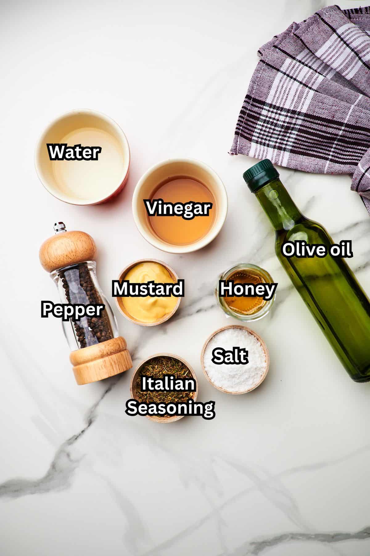 Ingredients for Italian sub dressing in small bowls on a countertop with labels.