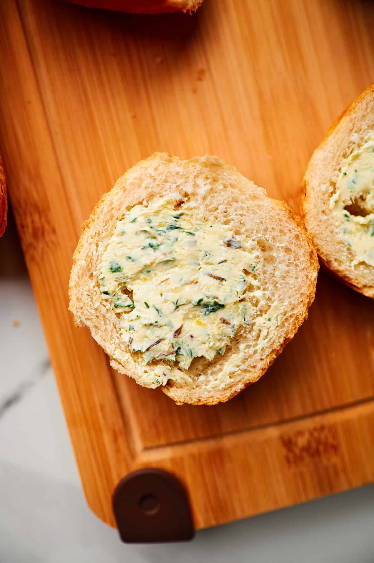 roasted garlic butter with herbs spread onto a baguette.