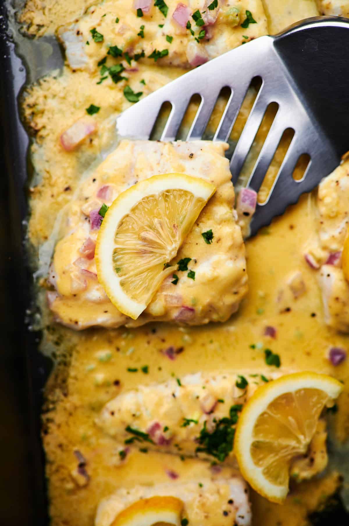 Overhead photo Baked Fish with Lemon Cream Sauce in a white baking dish, fresh out of the oven