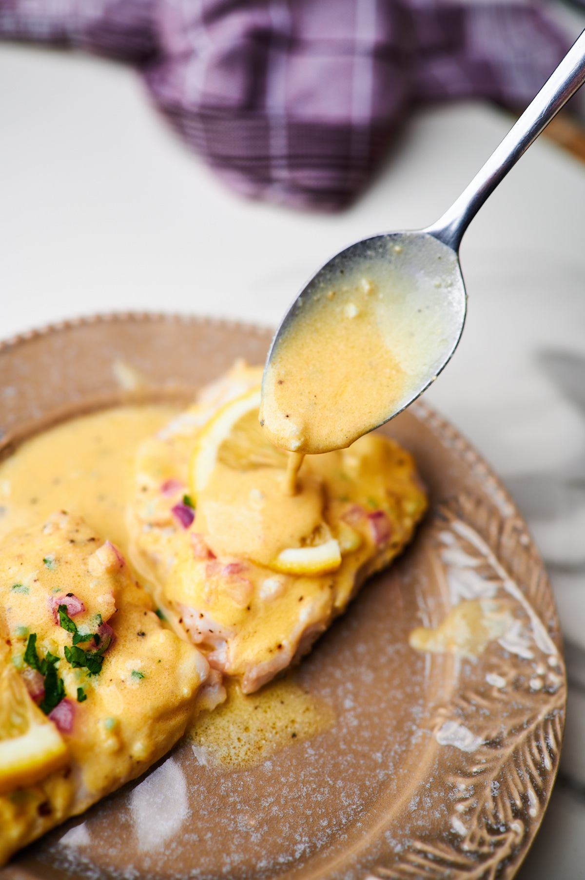 Spoon drizzling Lemon Cream Sauce over Baked Fish (one pan fish and sauce recipe!)