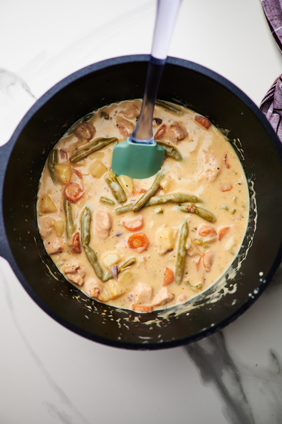 A soup pot filled with creamy chicken stew before and after being cooked.