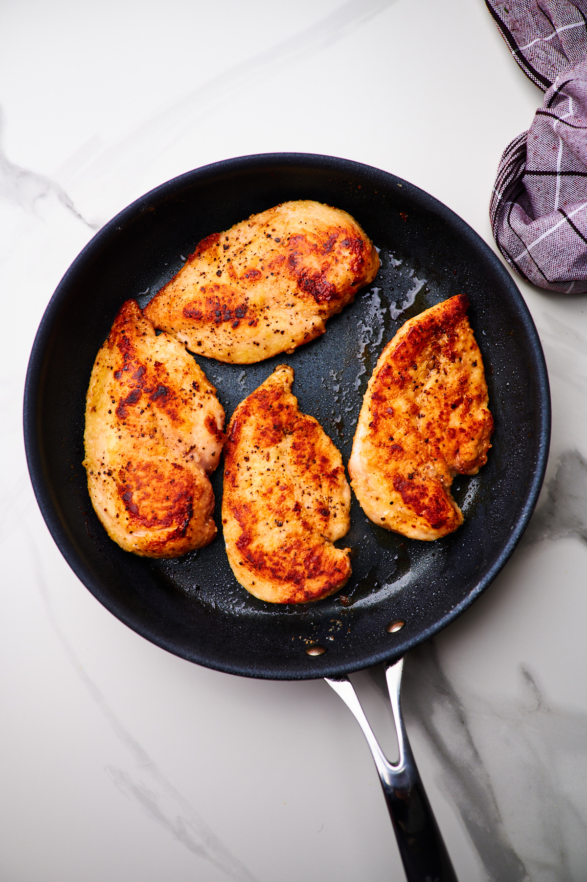 pan frying chicken in a cast iron skillet and then frying garlic cloves