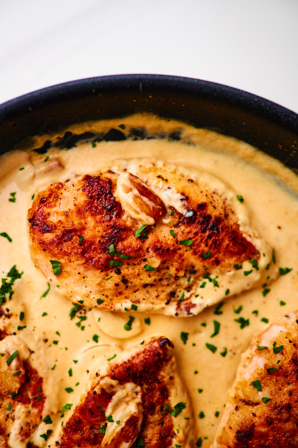 creamy garlic chicken in a cast iron skillet with whole garlic cloves and plenty of garlic cream sauce