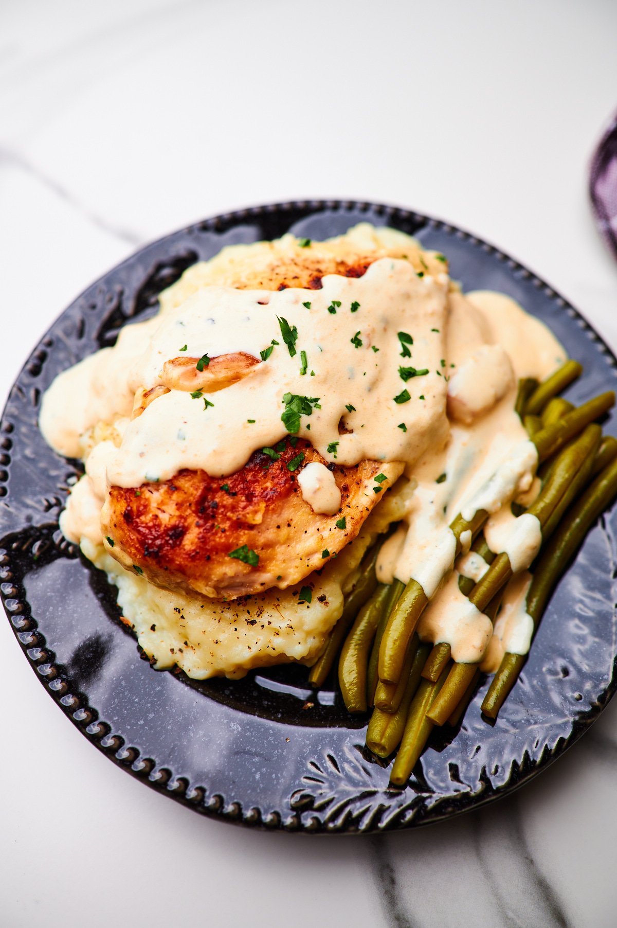 creamy garlic chicken on a plate with mashed potatoes and green beans