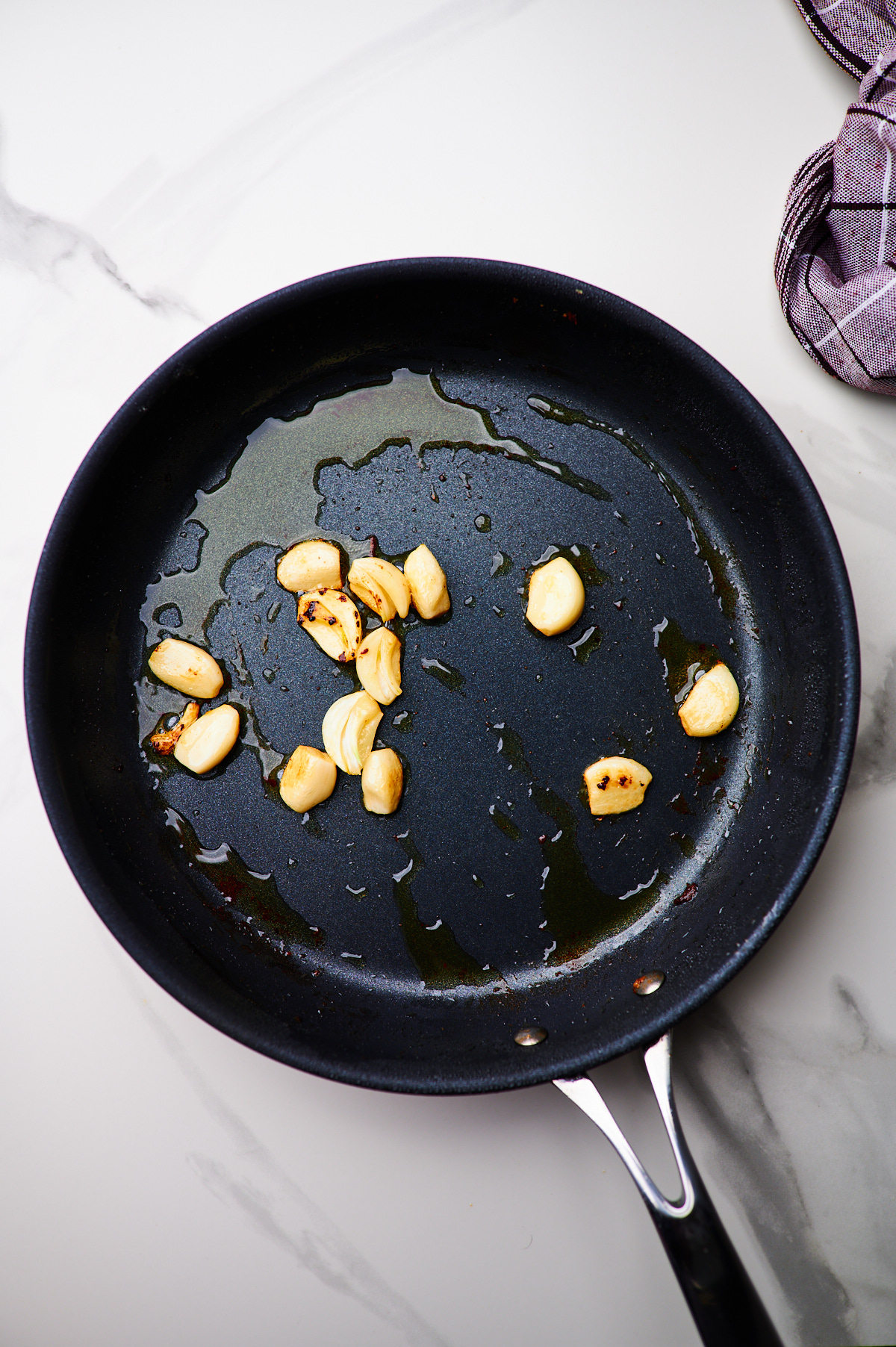 pan frying chicken in a cast iron skillet and then frying garlic cloves