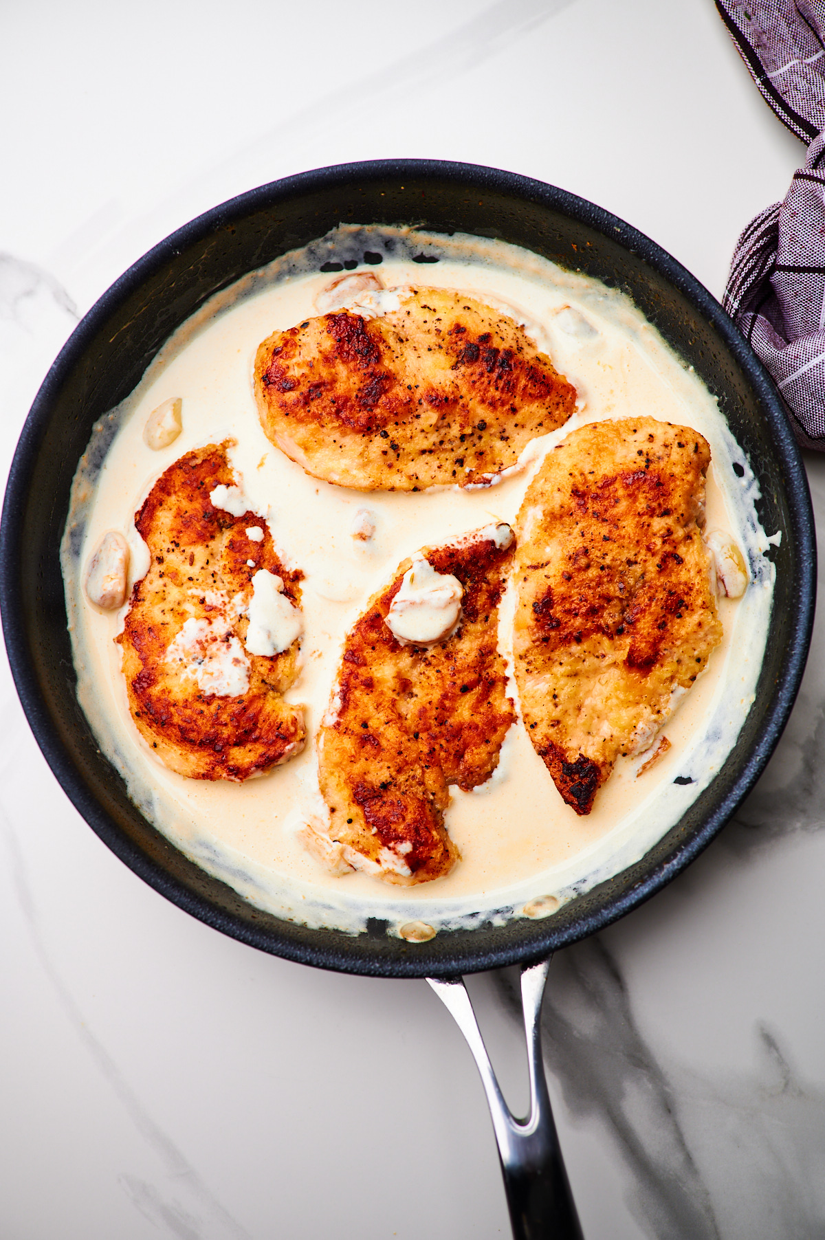 making sauce for creamy garlic chicken in a cast iron skillet